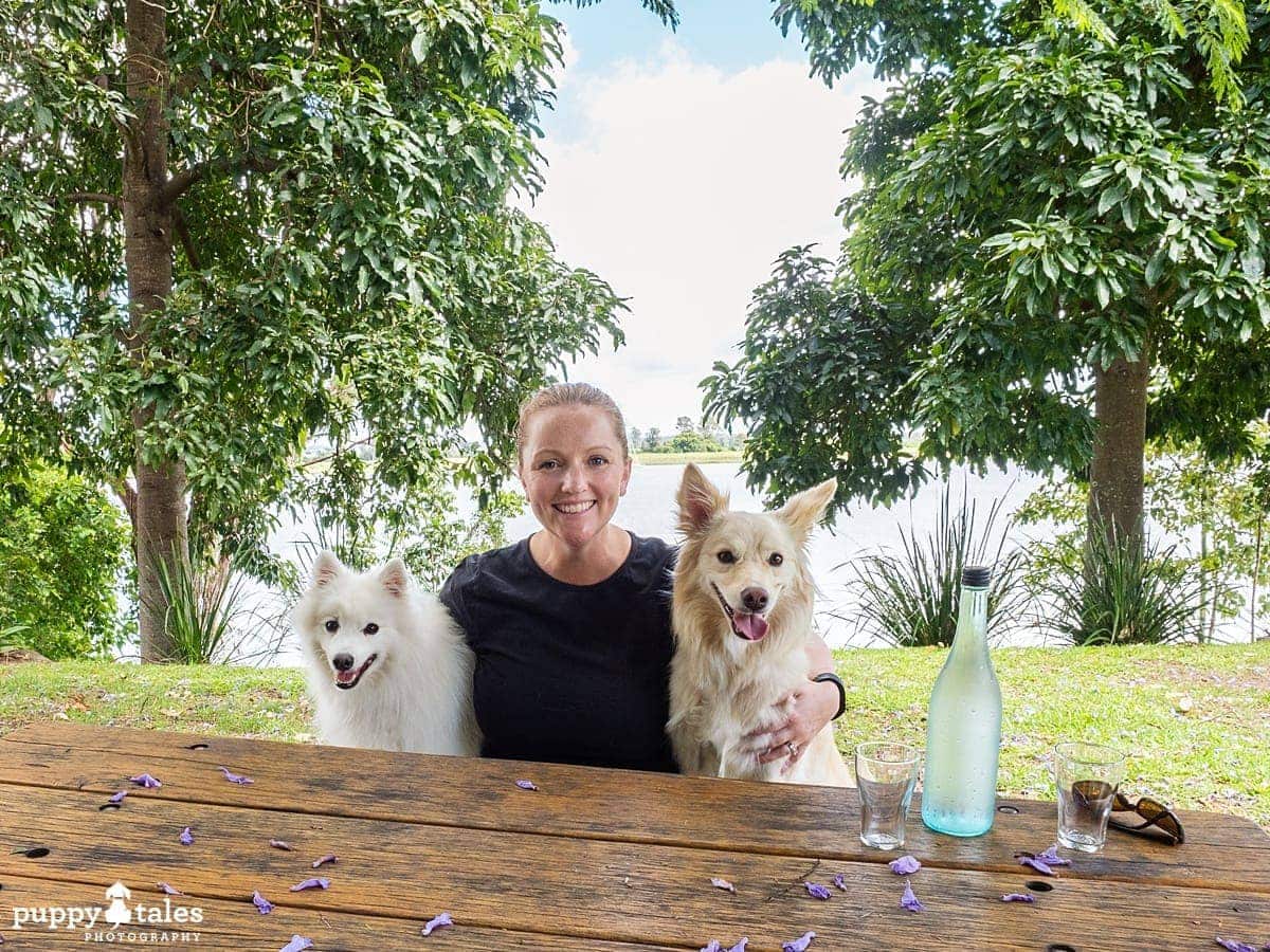a woman sitting at a table with her two dogs