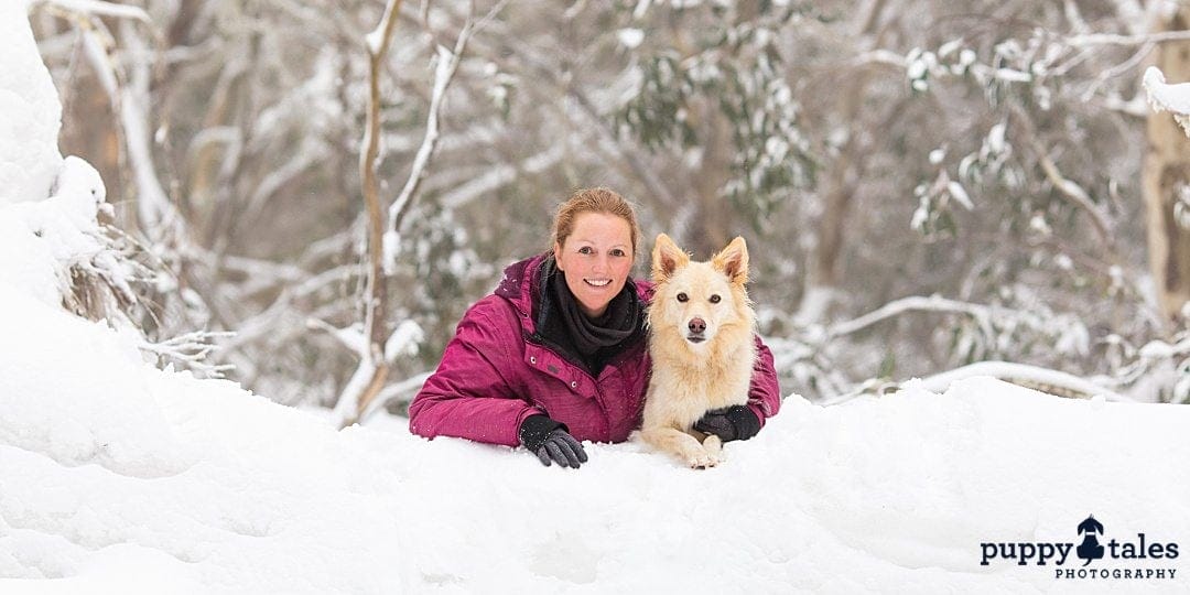 a woman wearing a winter jacket posing for the camera with her dog