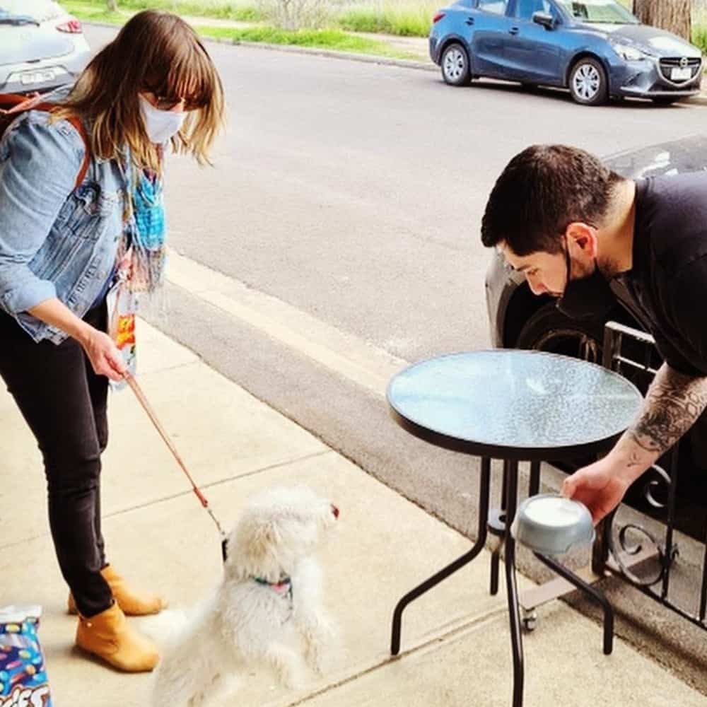 Two people interacting with a dog outside the dog friendly cafe in Melbourne