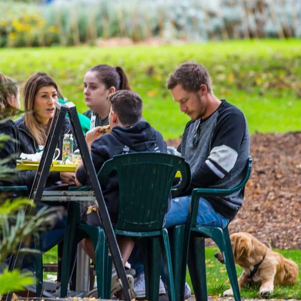 A group of people sat in the outdoor table of a pet friendly cafe in Melbourne's outer suburbs