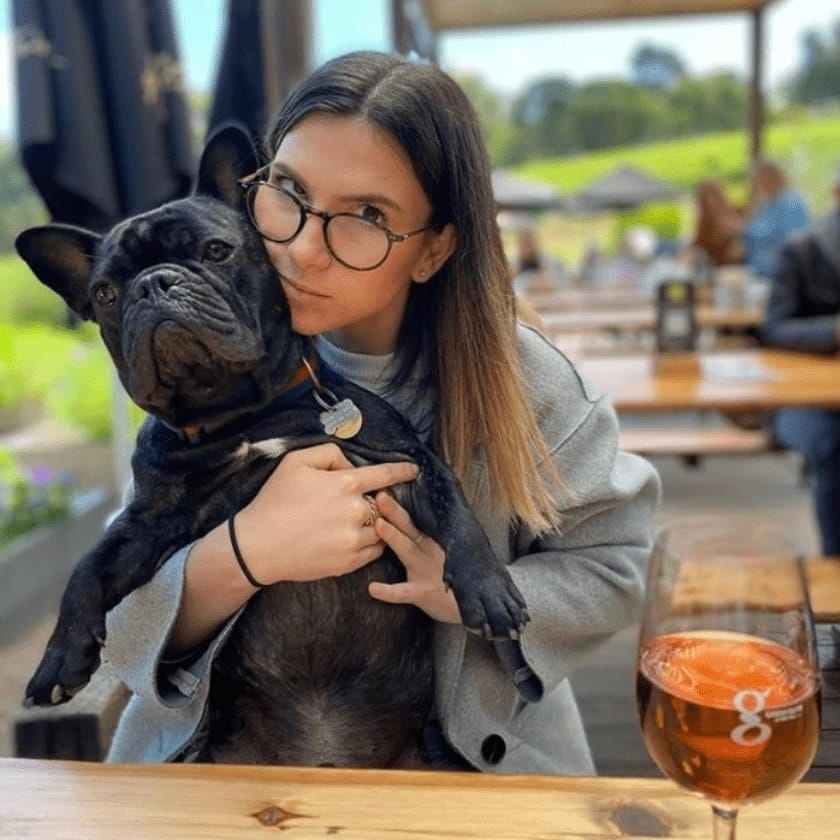 Woman holding her dog as she smiles for the camera in a dog friendly cafe in Melbourne