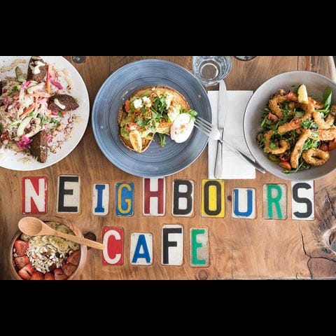 A delicious spread of food is captured at "Neighbours Cafe," a dog-friendly brunch spot in Melbourne. The name of the cafe adds a personal touch to the image.