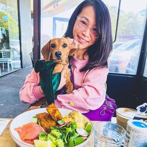 Owner posing with dog in one of the tables of a dog friendly cafe in melbourne with some food on the table