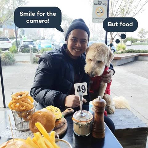 Owner and dog sitting outside a dog friendly cafe around Melbourne with some food on the table