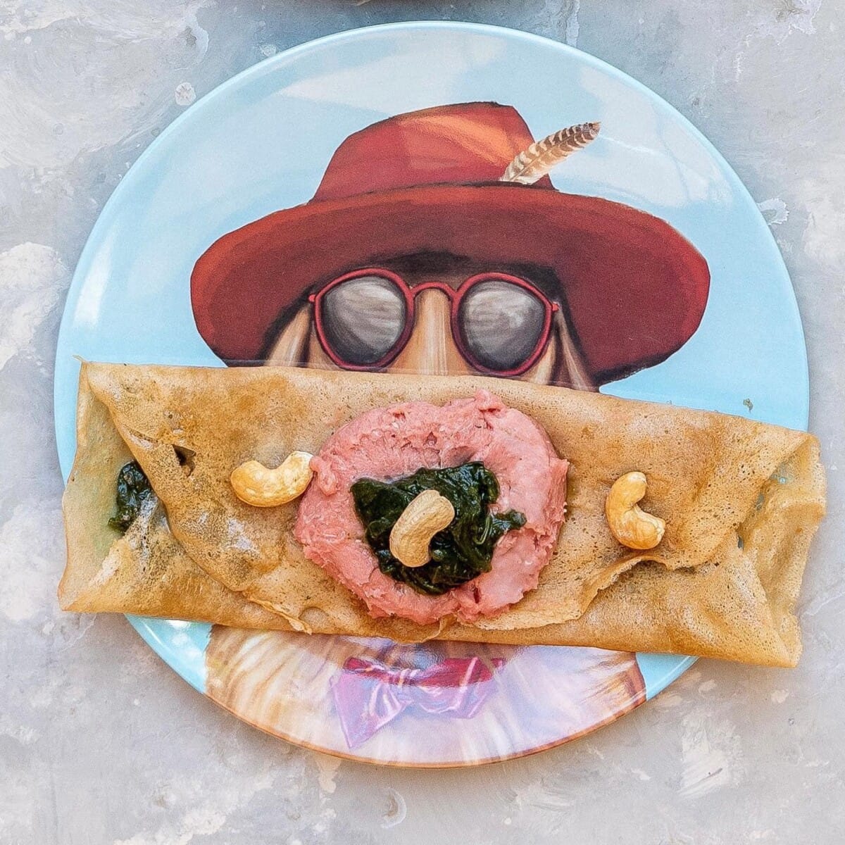 At a dog-friendly cafe in Melbourne, a charming plate featuring a whimsical illustration of a dog in a red hat serves as the backdrop for a delicious crepe, making for a memorable and tasty meal.