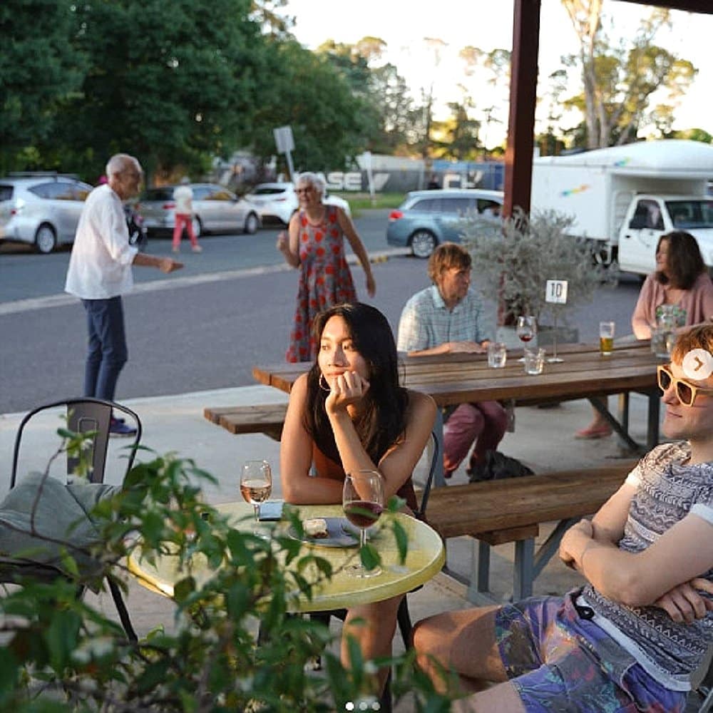 A group of people hanging outdoors in the spacious tables and chairs of Gang Gang Cafe in Canberra